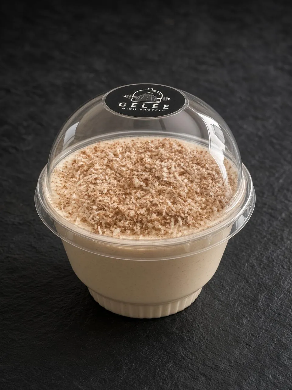 Gelée alta en proteína sabor coco, en vaso individual con tapa de domo y coco rallado espolvoreado